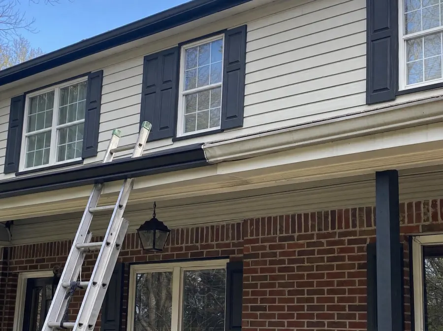 Gutter replacement in progress on an older Fairburn, GA home — new black seamless runs replacing aging sectional gutters