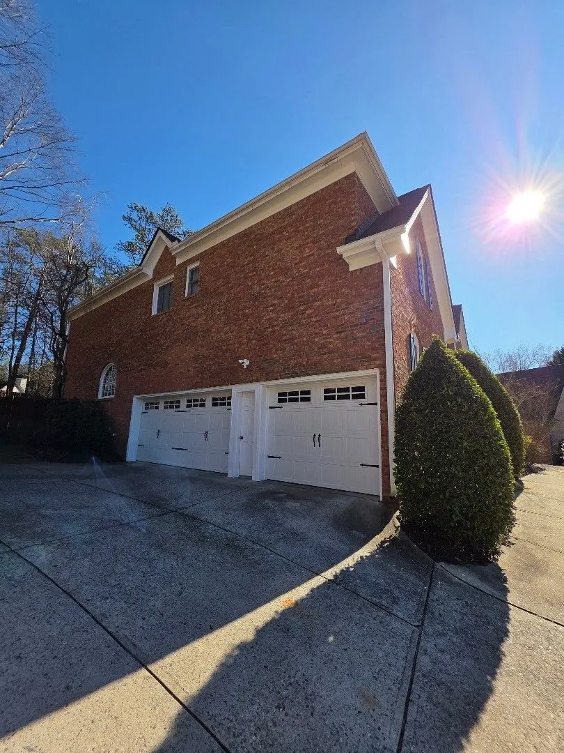 Brick garage wing with white gutters along the eaves and a downspout at the corner, in Alpharetta, GA