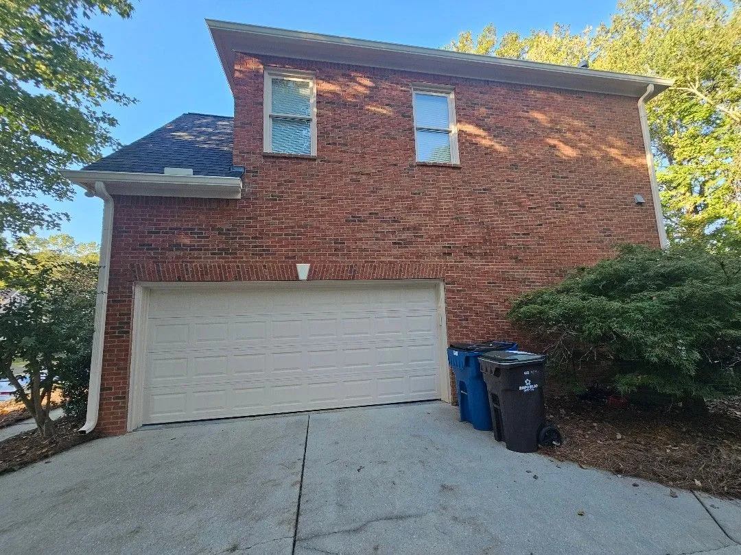 Garage side of the brick home with gutters along the eaves and a downspout at each corner, in Alpharetta, GA