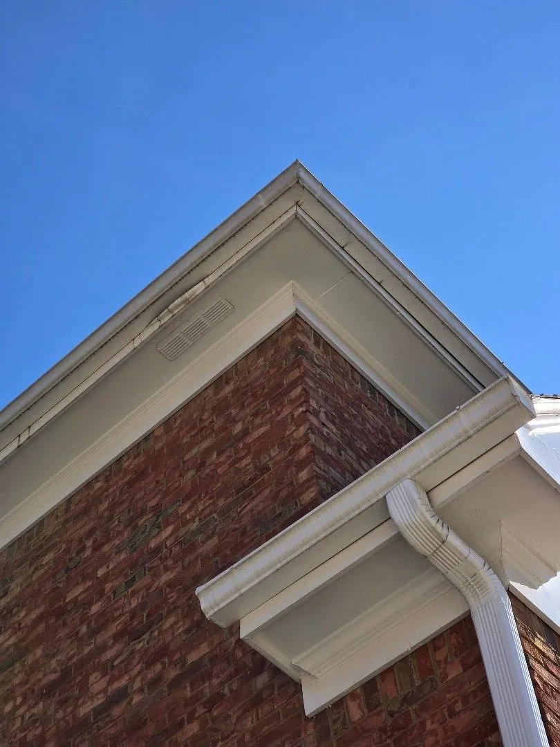 Close-up of a gutter corner, soffit vent and downspout elbow at a brick corner, in Alpharetta, GA
