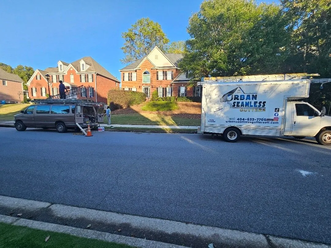 Urban Seamless Gutters truck and crew van on an Alpharetta, GA street lined with two-story brick homes