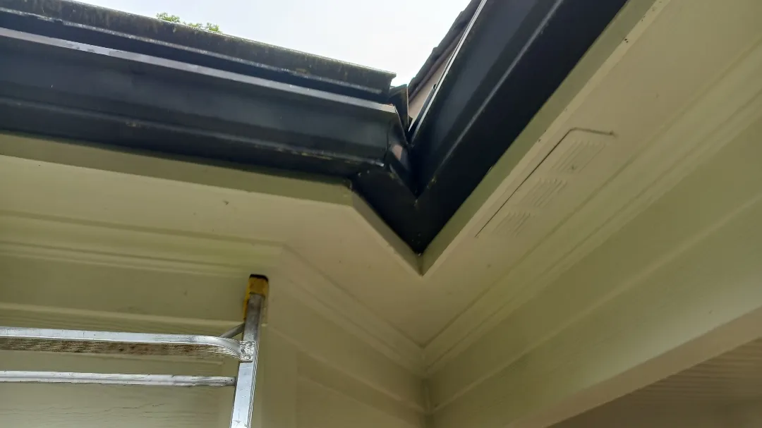 Gutter corner seen from under the eave, above light siding and trim, on an Alpharetta, GA home