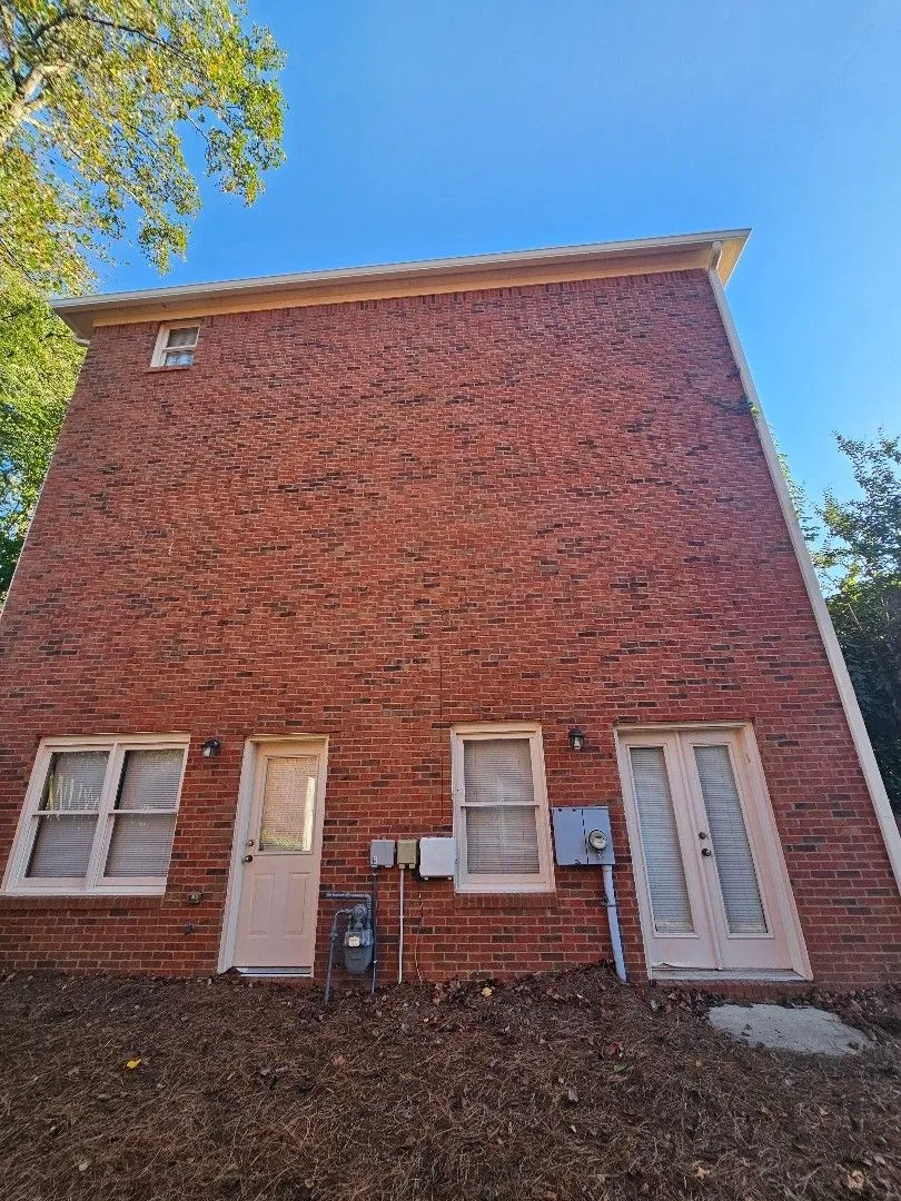 Tall brick side wall with a gutter at the roofline and a downspout down the corner, in Alpharetta, GA