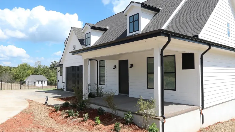 New-construction modern farmhouse with clean black seamless gutter lines — Mableton, GA