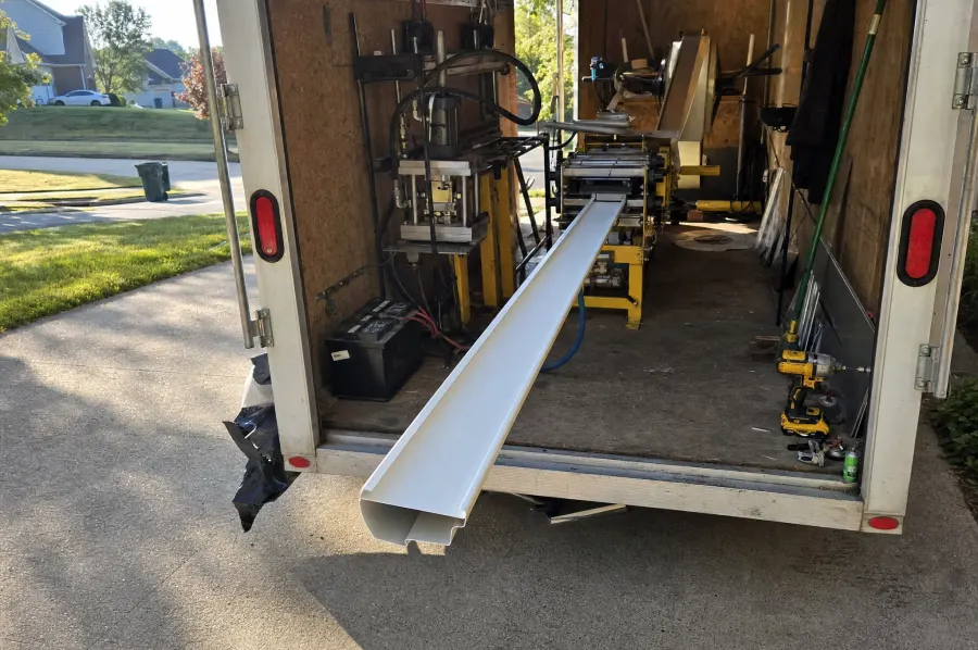 Seamless gutter forming machine rolling a continuous length of aluminum gutter on site at an Atlanta, GA home