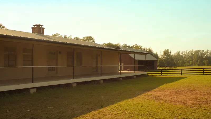 Coweta County farmhouse on open acreage with long black seamless gutter runs across house and porch — Sharpsburg, GA