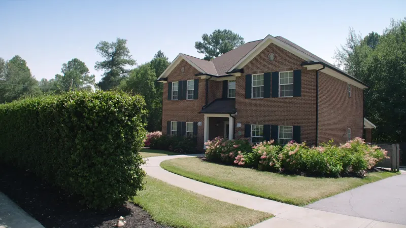 Henry County brick two-story with right-sized black seamless gutters and crepe myrtles along the drive — Stockbridge, GA