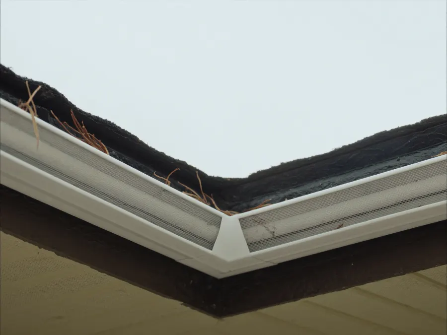 Low-profile micro-mesh gutter guards keeping pine needles out of white seamless gutters on a Suwanee, GA home